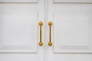 White church doors with golden handles. Closeup
