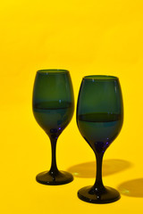 Two blue wine glasses on a yellow background