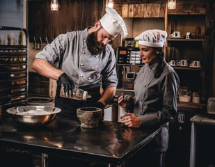 Chef pours sesame into a mortar. Cooking lesson in bakery.