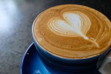 Close up of a cup of cafe latte coffee in a blue ceramic cup on black metal table
