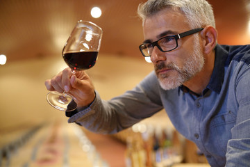 Winemaker tasting red wine in cellar