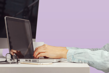 Young woman sitting at the table with open netbook computer. Female person using modern technology.