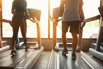Fototapeta na wymiar Cropped shot of People running in machine treadmill at fitness gym club movement and morning light.