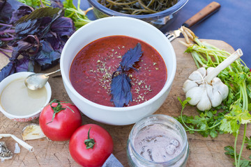 Vegan tomato soup with beetroot juice and coconut cream, basil leaves. 