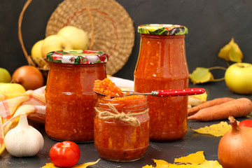 Homemade adzhika with apples in jars on a dark background Open jar with adzhika. Harvesting for the winter