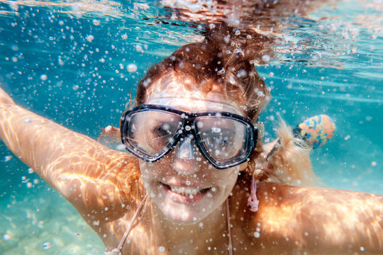 Smiling woman with mask underwater snorkeling in the clear tropical water