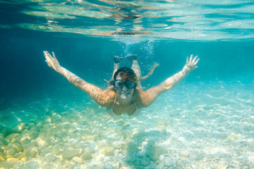 Smiling woman with mask underwater snorkeling in the clear tropical water