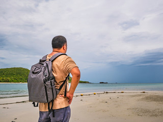 Asian fat Backpacker stand on the idyllic beach with Rainy cloud Sky in vacation time.Samae San Island thailand.Summer concept.