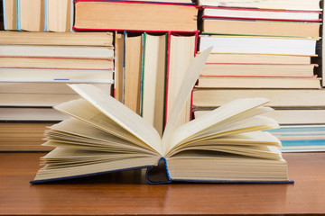 Open book on wooden table against background of other books