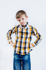 Little boy in a checked shirt on a white background meditates and hands on his hips