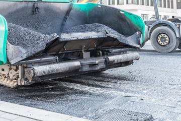Nahaufnahme eines Asphaltfertiger auf einer Baustelle bei der Erneuerung der Fahrbahndecke,...