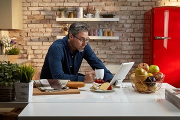 Older man having breakfast in kitchen - Powered by Adobe