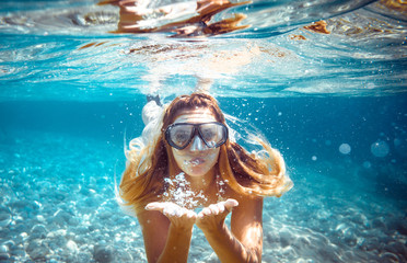 Snorkeling woman blowing a kiss underwater in the tropical sea - obrazy, fototapety, plakaty