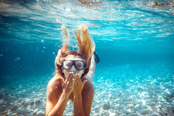 Snorkeling woman blowing a kiss underwater in the tropical sea