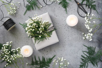 Christmas wrapping gift box among plants and white candles, florist workshop, photo set. Flat lay, top view. The concept of New Year Holidays.