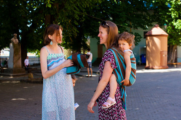 Mother carrying her baby meeting a friend
