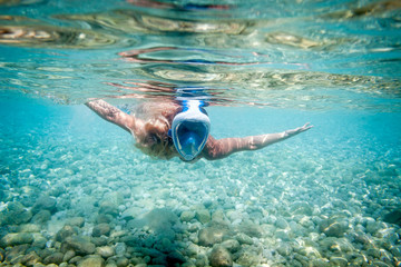 Woman snorkeling with full face mask in the tropical sea