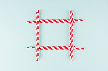 Minimalist modern art abstract background - red striped straws on light soft mint colors paper as blank square frame.