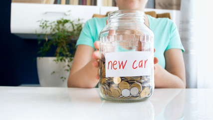 Closeup photo of young woman holding glass jar full of money for buying new car