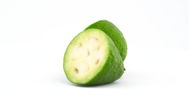 Two halves of mature feijoa fruit with water drops. Rotating on the turntable isolated on the white background. Close up. Macro.