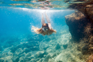 Young woman snorkeling underwater in the clear tropical water