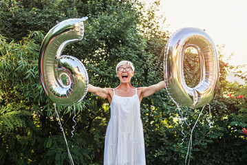 Senior woman celebrating her 60th birthday, with balloons 