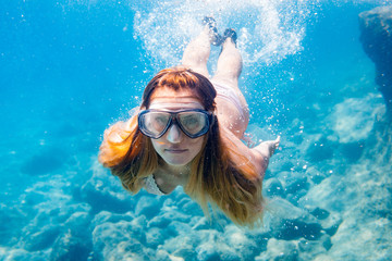 Fototapeta premium Young woman snorkeling underwater in the clear tropical water