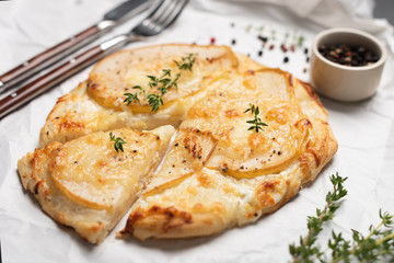 Pizza with pear and blue cheese garnished with fresh thyme and pepper. Closeup view. Mini pizza,...