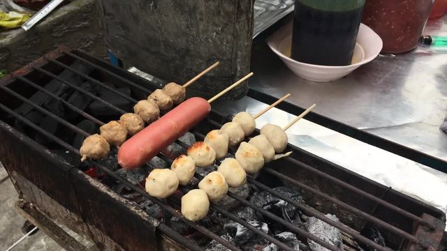 Cooking concept : Row pork balls and sausage in stick on stove grilled with fire and charcoal, Thai delicious pork balls . Popular street food