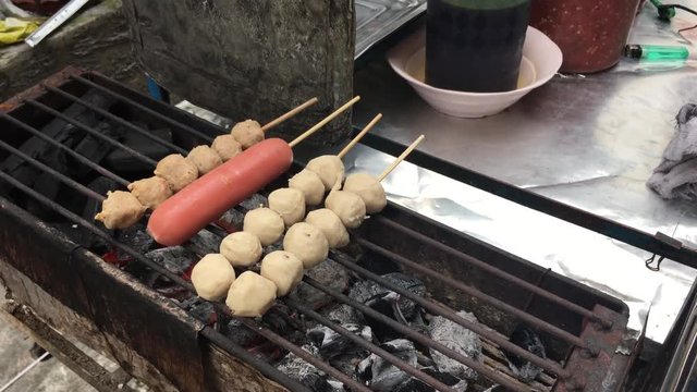 Cooking concept : Row pork balls and sausage in stick on stove grilled with fire and charcoal, Thai delicious pork balls . Popular street food