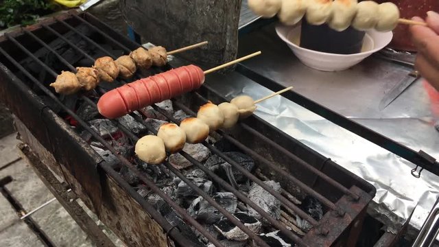 Cooking concept : Row pork balls and sausage in stick on stove grilled with fire and charcoal, Thai delicious pork balls . Popular street food