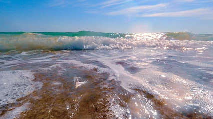 The wave runs on the beach in summer on a Sunny day