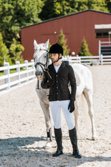 handsome male equestrian standing near horse and looking away at horse club