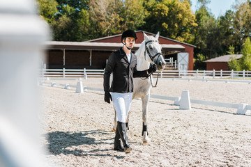 handsome male equestrian walking near horse at horse club