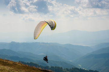 Paraglider takes off from the mountainside in the Carpathian Mountains. Paragliding in the...