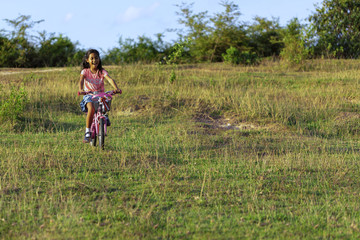 A female schoolchild fun with bicycle in the park.