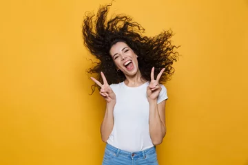 Deurstickers Image of european woman 20s laughing and having fun with shaking hair, isolated over yellow background © Drobot Dean