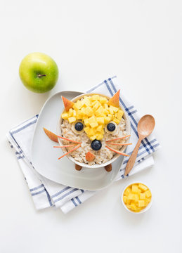 Naklejki Oatmeal porridge with cute funny face, kids breakfast. Good morning breakfast for kids, food art. White background