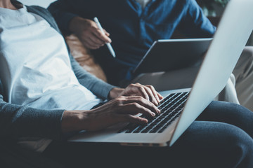 Man and woman in office studio together, using digital devices and laptops