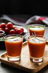 Seasonal tomato soup gazpacho in glasses on dark wooden table background. Vertical. Food and drink, still life, diet and nutrition concept. Meditteranean food.