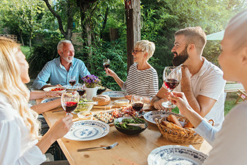 Family cheering over the dining table outdoors, celebration 