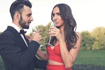 Happy couple of lovers with a glass of wine or champagne standing outdoors.