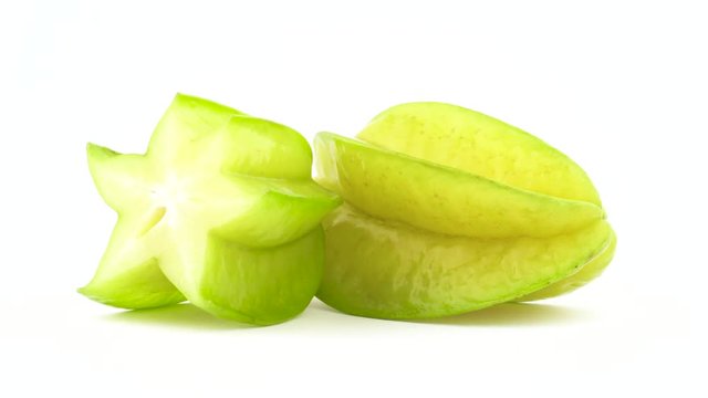 One whole and one half of carambola fruit. Rotating on the turntable isolated on the white background. Close up. Macro.