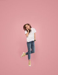 Always on mobile. Full length of pretty surprised young woman taking phone while jumping against pink studio background. Mobile, motion, movement, business concepts