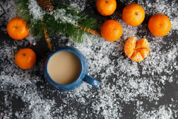Fototapeta na wymiar Christmas and New Year's concept. Mandarins, coffee mug, snow, Christmas tree branch. Against a dark background