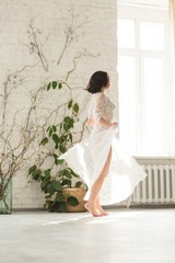 Young beautiful bride dancing near the big window