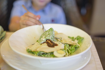 little boy eating salad in cafe