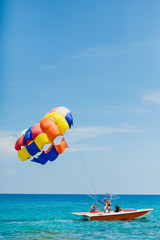 Couple of tourists flying on a colorful parachute