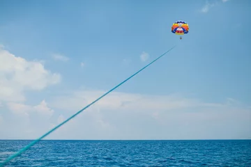 Crédence de cuisine en verre imprimé Sports nautique Personnes volant sur un parachute coloré remorqué par un bateau à moteur