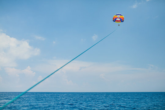 People flying on a colorful parachute towed by a motor boat